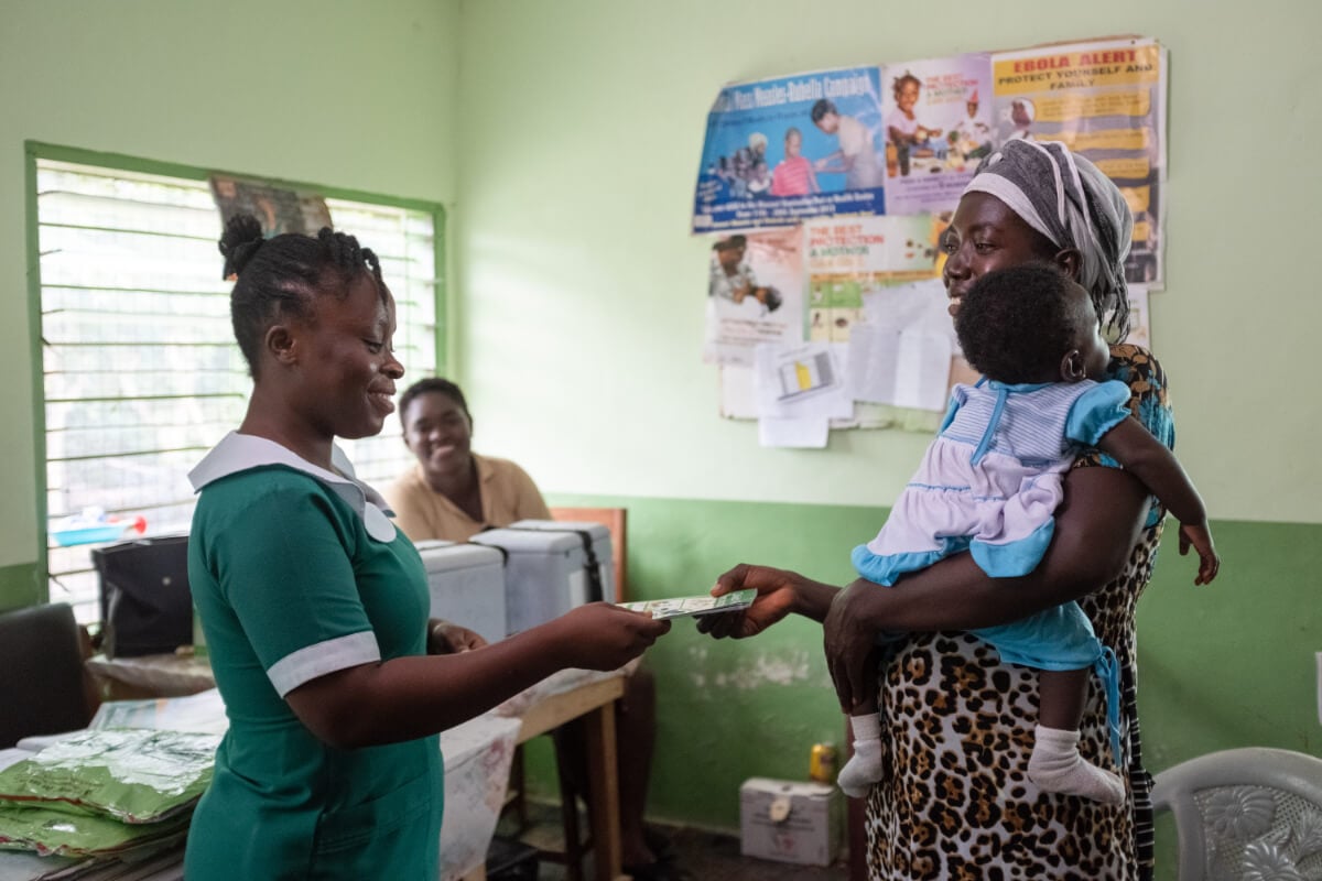 A mother receives an updated records book for her 6 months old daughter after being vaccinated at the community clinic.